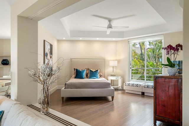 bedroom featuring wood-type flooring, a raised ceiling, and ceiling fan