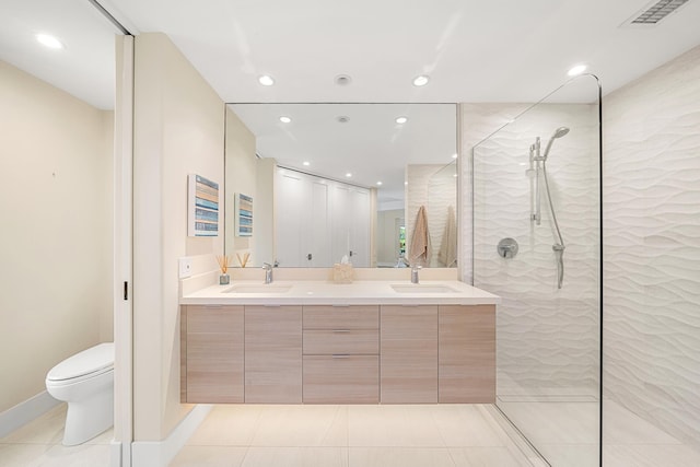 bathroom featuring a tile shower, vanity, tile patterned flooring, and toilet