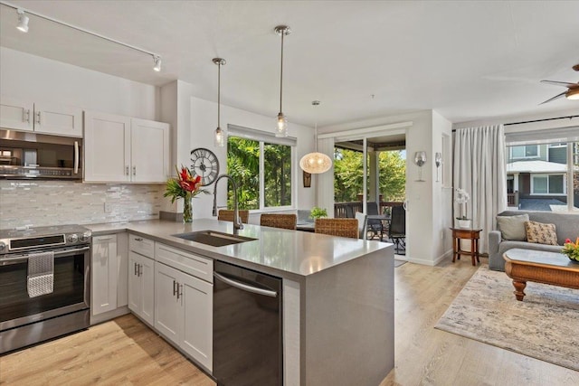 kitchen with white cabinets, kitchen peninsula, appliances with stainless steel finishes, and sink