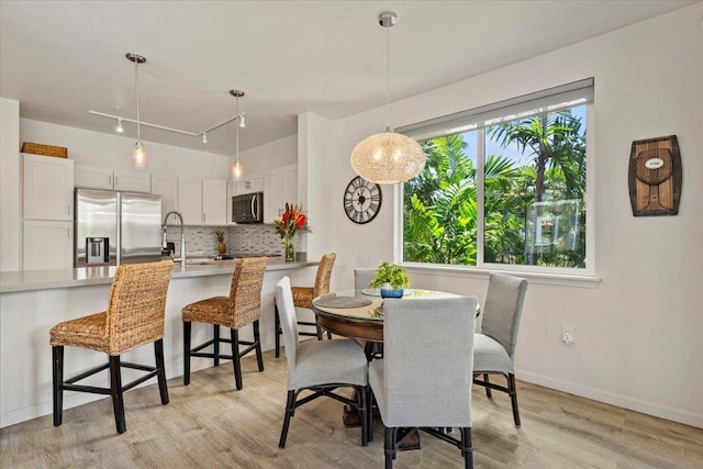 dining space with light hardwood / wood-style floors and track lighting