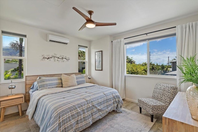 bedroom featuring light hardwood / wood-style floors, a wall mounted air conditioner, and ceiling fan