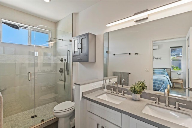 bathroom featuring toilet, a shower with door, vanity, and a healthy amount of sunlight