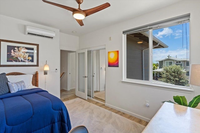 bedroom with a closet, ceiling fan, a wall mounted AC, and light hardwood / wood-style flooring