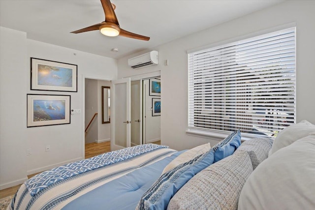 bedroom with an AC wall unit, multiple windows, ceiling fan, and light wood-type flooring