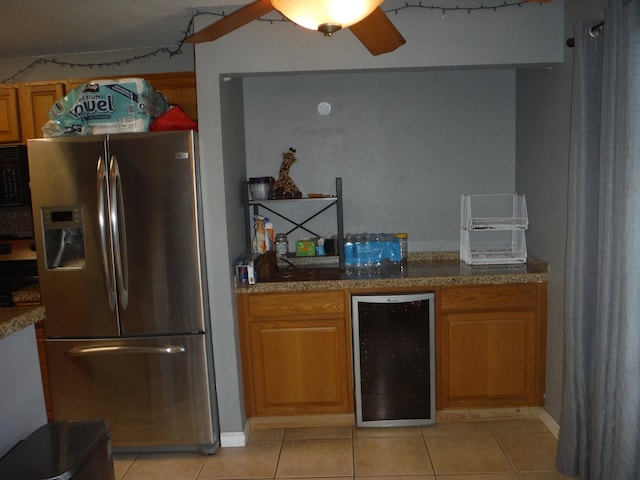 kitchen with light stone counters, wine cooler, light tile patterned floors, black microwave, and stainless steel fridge with ice dispenser