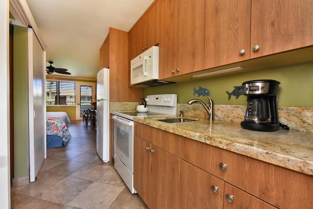 kitchen with ceiling fan, light stone countertops, white appliances, and sink