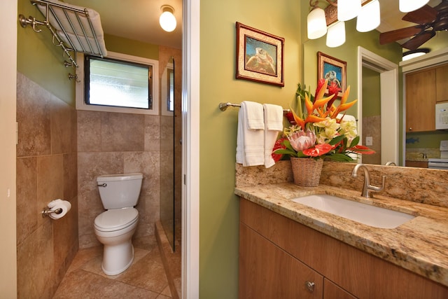 bathroom with tile patterned flooring, vanity, toilet, and tile walls