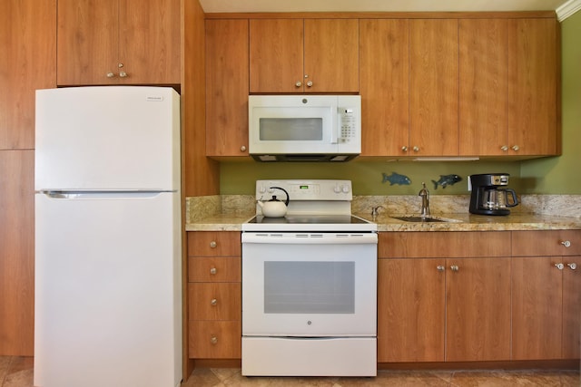 kitchen with light stone countertops, white appliances, and sink