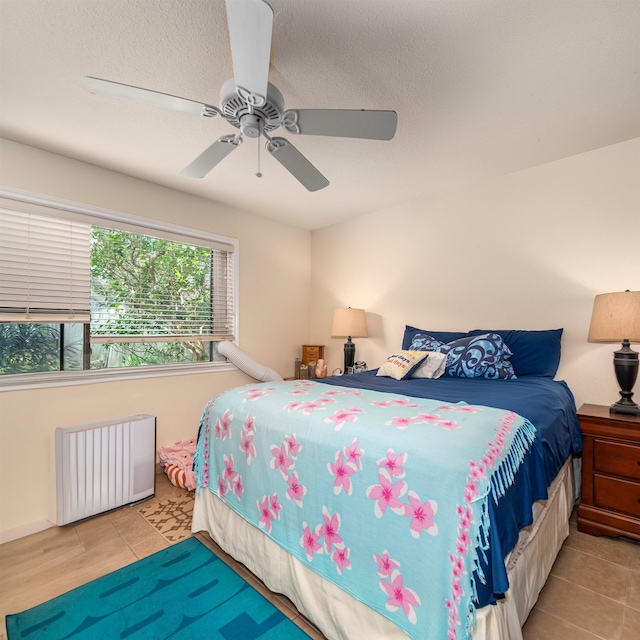 tiled bedroom featuring a textured ceiling, radiator, and ceiling fan