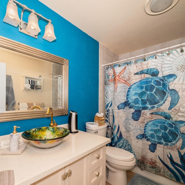 bathroom featuring a textured ceiling, vanity, toilet, and a shower with curtain