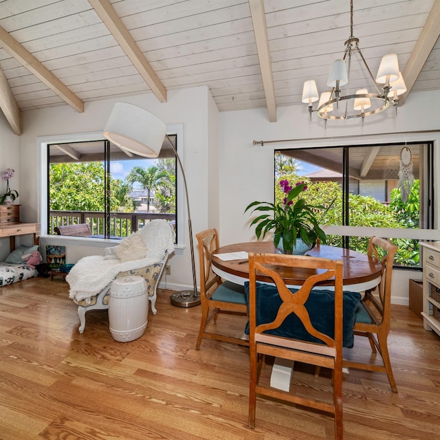 dining room featuring light hardwood / wood-style floors, lofted ceiling with beams, an inviting chandelier, and plenty of natural light