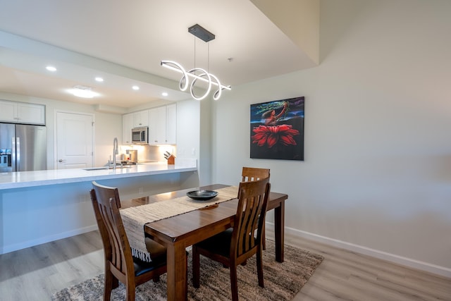 dining room with sink, light hardwood / wood-style flooring, and a chandelier