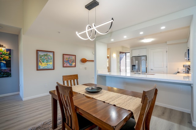 dining room with sink, a notable chandelier, and light hardwood / wood-style floors