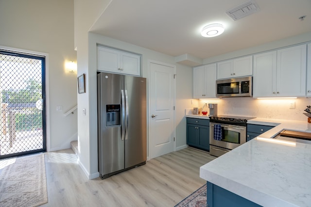 kitchen featuring stainless steel appliances, white cabinetry, blue cabinetry, and light hardwood / wood-style flooring