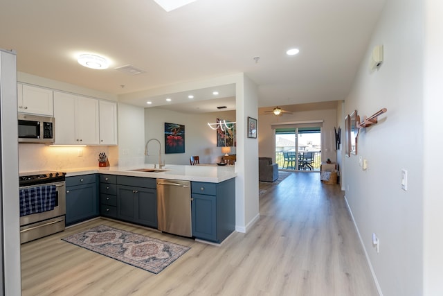 kitchen featuring appliances with stainless steel finishes, tasteful backsplash, white cabinetry, sink, and light wood-type flooring