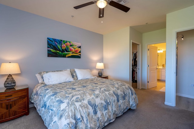 carpeted bedroom featuring ensuite bath, a walk in closet, a closet, and ceiling fan