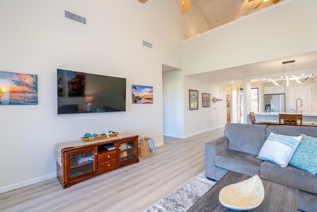 living room featuring light hardwood / wood-style flooring, ceiling fan, and a high ceiling