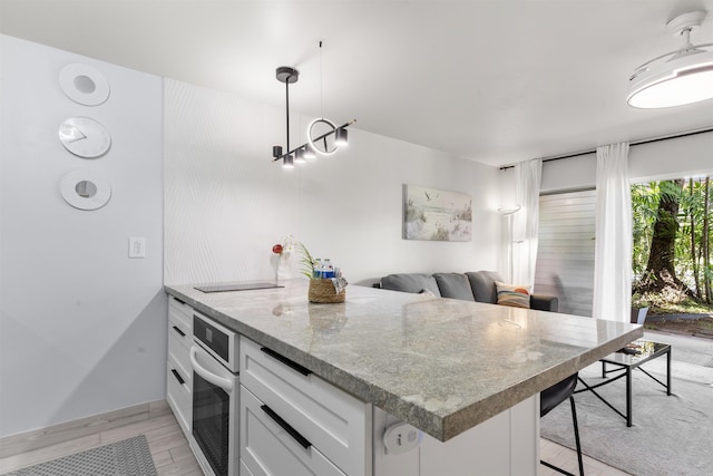 3559 Lower Honoapiilani Rd Unit 709, Lahaina, HI 96761 - kitchen featuring oven, a breakfast bar, pendant lighting, a peninsula, and white cabinetry