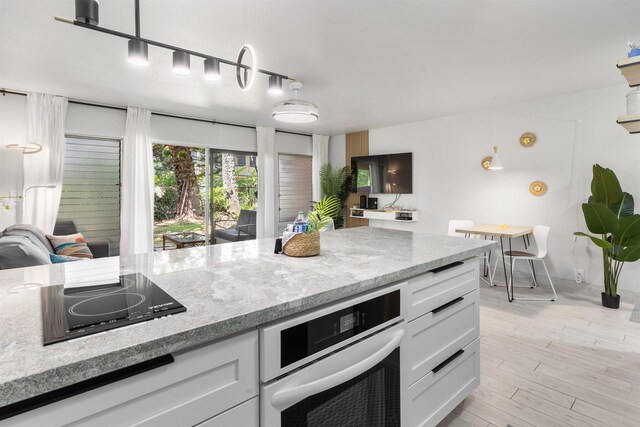 3559 Lower Honoapiilani Rd Unit 709, Lahaina, HI 96761 - kitchen with white cabinets, black electric cooktop, white oven, and light stone counters