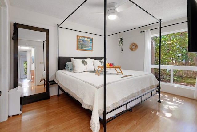 bedroom featuring multiple windows, ceiling fan, a textured ceiling, and hardwood / wood-style flooring