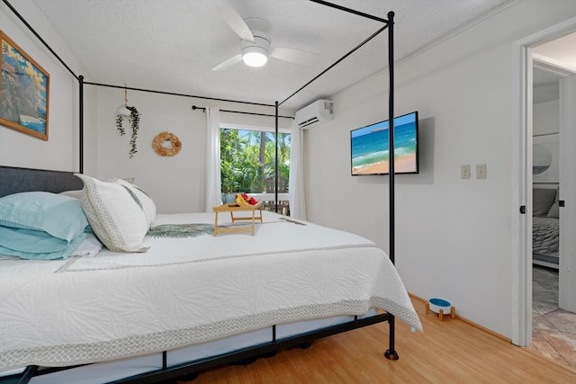 bedroom featuring a textured ceiling, hardwood / wood-style flooring, an AC wall unit, and ceiling fan