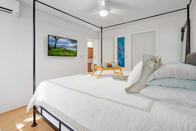 bedroom with a wall mounted AC, wood-type flooring, a textured ceiling, and ceiling fan