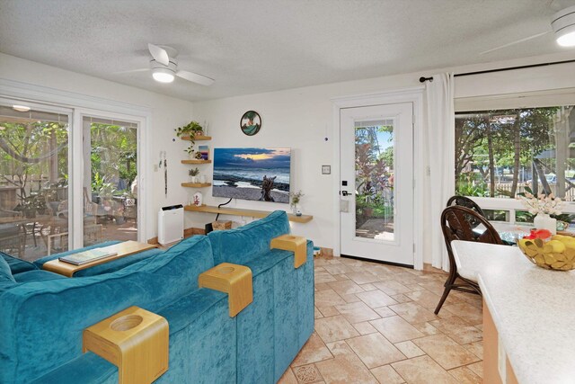 living room with a textured ceiling, ceiling fan, and a healthy amount of sunlight