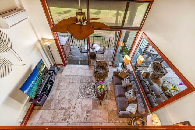 living room with ceiling fan, a wall unit AC, and a healthy amount of sunlight