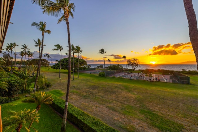 yard at dusk featuring a water view