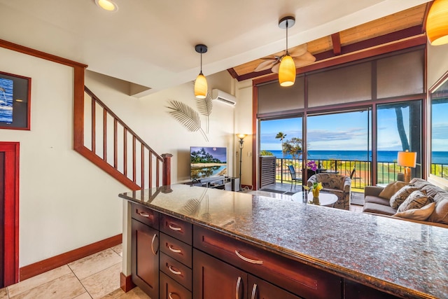 kitchen featuring dark stone counters, beam ceiling, hanging light fixtures, a wall mounted AC, and light tile patterned floors