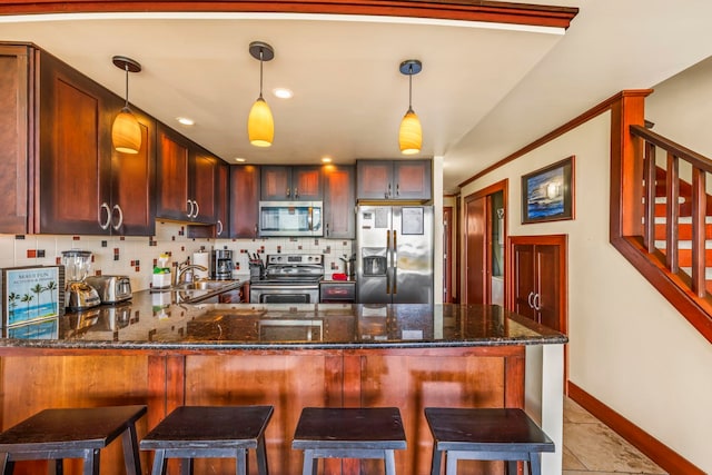 kitchen featuring stainless steel appliances, tasteful backsplash, kitchen peninsula, pendant lighting, and a kitchen breakfast bar