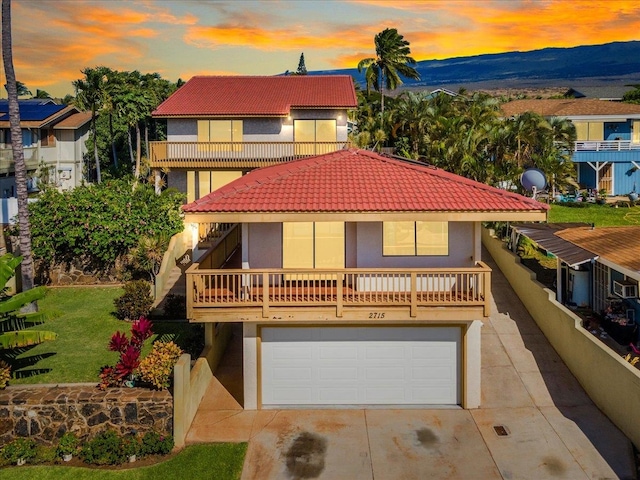 view of front of house featuring a mountain view, a yard, a garage, and a balcony