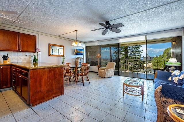 kitchen featuring ceiling fan, tasteful backsplash, a textured ceiling, light tile floors, and hanging light fixtures