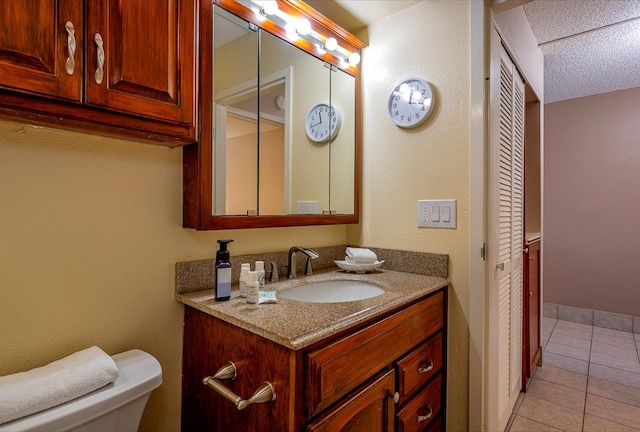 bathroom with tile floors, a textured ceiling, toilet, and large vanity