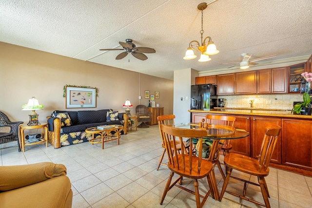 tiled dining area featuring ceiling fan with notable chandelier and a textured ceiling