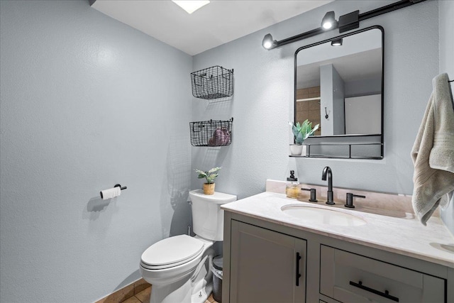 bathroom with vanity, toilet, and a textured wall