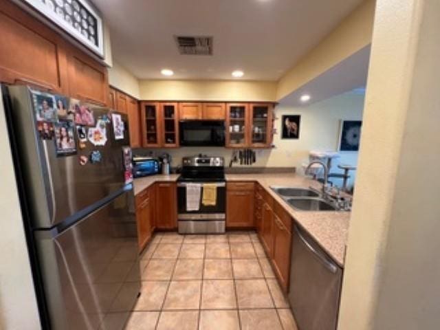 44 Kanani Rd Unit 1-104, Kihei, HI 96753 - kitchen featuring appliances with stainless steel finishes, brown cabinets, glass insert cabinets, light tile patterned floors, and light countertops