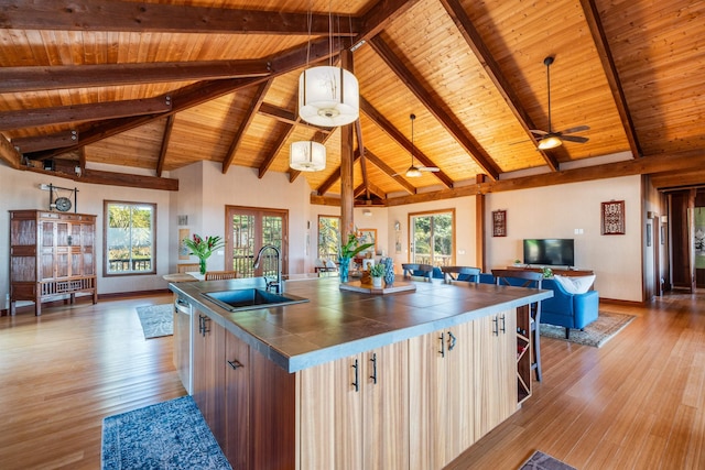 kitchen featuring an island with sink, sink, beamed ceiling, and wood ceiling