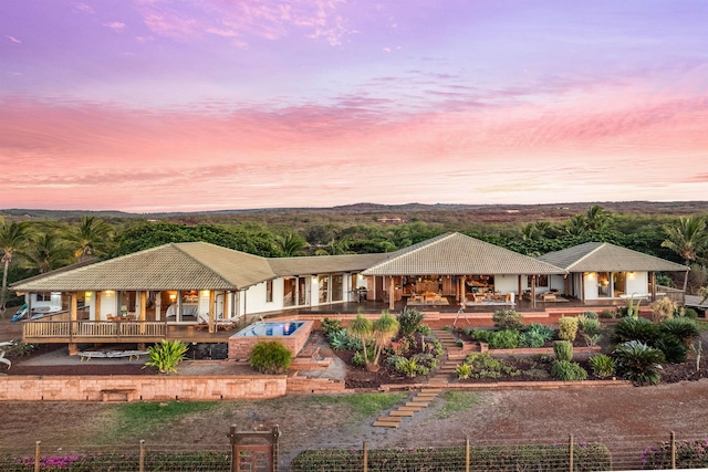 back house at dusk featuring a patio and a pool