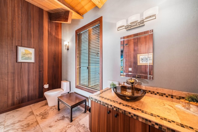 bathroom featuring wood ceiling, vanity, wooden walls, lofted ceiling with beams, and toilet