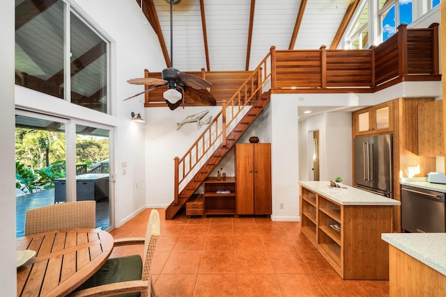 interior space with appliances with stainless steel finishes, a towering ceiling, light tile patterned floors, and ceiling fan