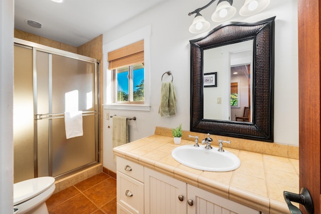 bathroom with tile patterned flooring, vanity, toilet, and walk in shower