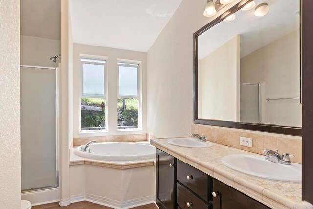 bathroom with shower with separate bathtub, vanity, and lofted ceiling