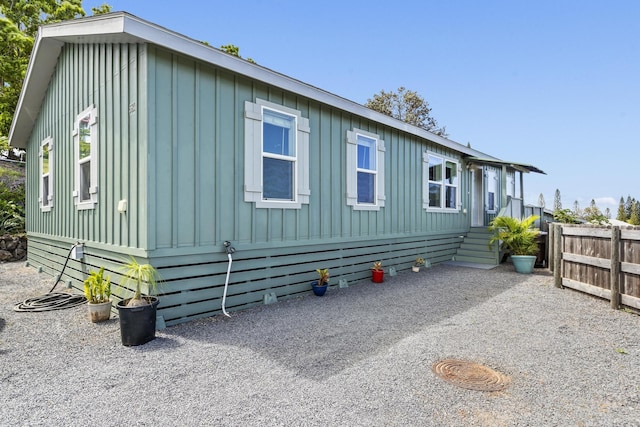 view of property exterior featuring board and batten siding and fence