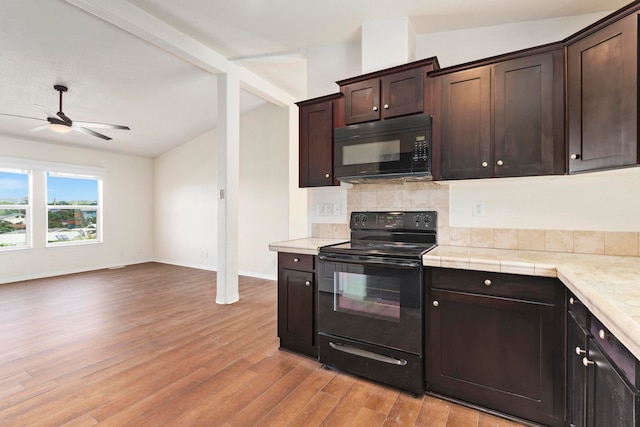 kitchen with dark brown cabinets, light hardwood / wood-style floors, lofted ceiling, and black appliances