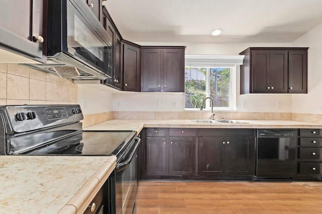 kitchen with backsplash, black appliances, sink, light hardwood / wood-style flooring, and dark brown cabinets