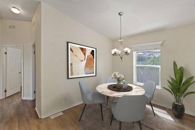 dining space featuring visible vents, wood finished floors, and a chandelier