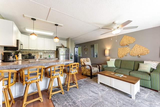 kitchen with stainless steel appliances, white cabinets, a kitchen bar, and kitchen peninsula