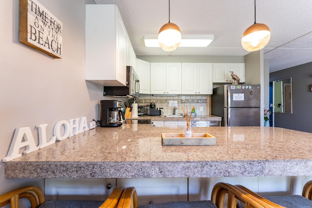 kitchen with stainless steel appliances, hanging light fixtures, a breakfast bar, and white cabinets