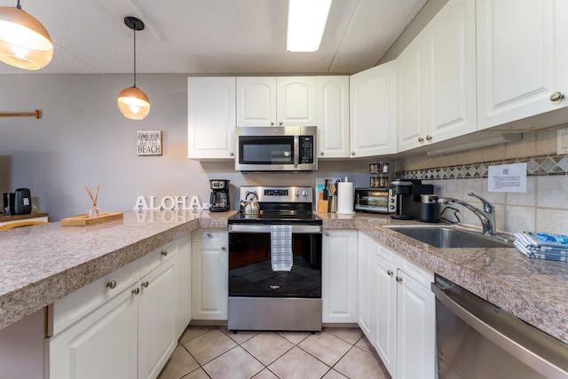 kitchen with sink, white cabinetry, light tile patterned floors, appliances with stainless steel finishes, and pendant lighting